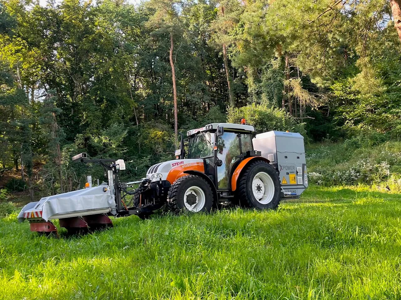 Steyr-Traktor mit XPower XPU – Frontgerät und heckseitiger Stromerzeuger im Grünflächeneinsatz